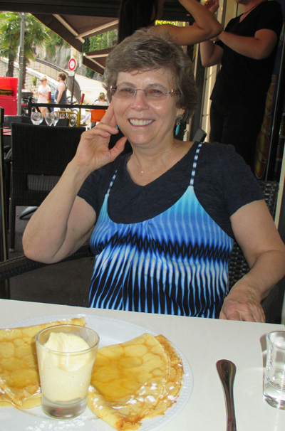 Photo shows Dona smiling with a plate of crepes and a small cup of vanilla ice cream.